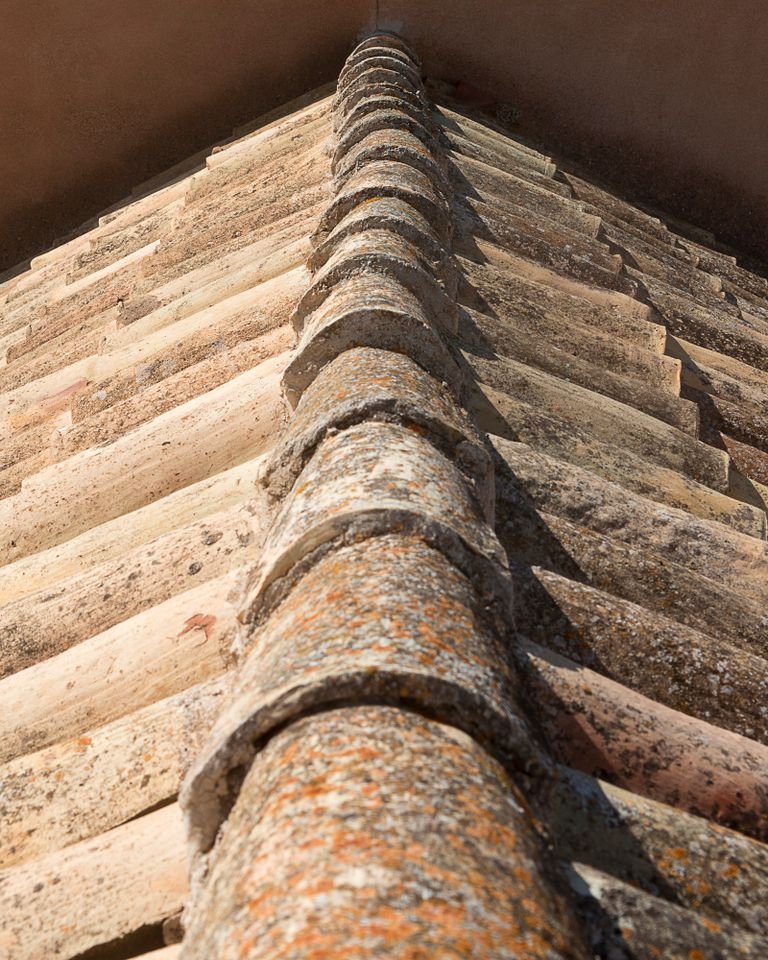 Weathered ridge capping along the hip of a tiled roof