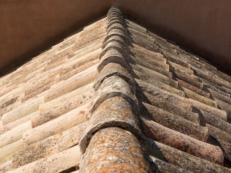 Weathered ridge capping along the hip of a tiled roof