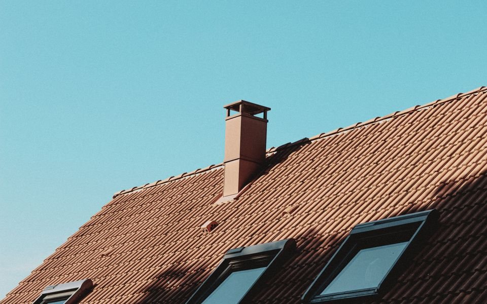 Terracotta tiled roof with a chimney and three roof windows