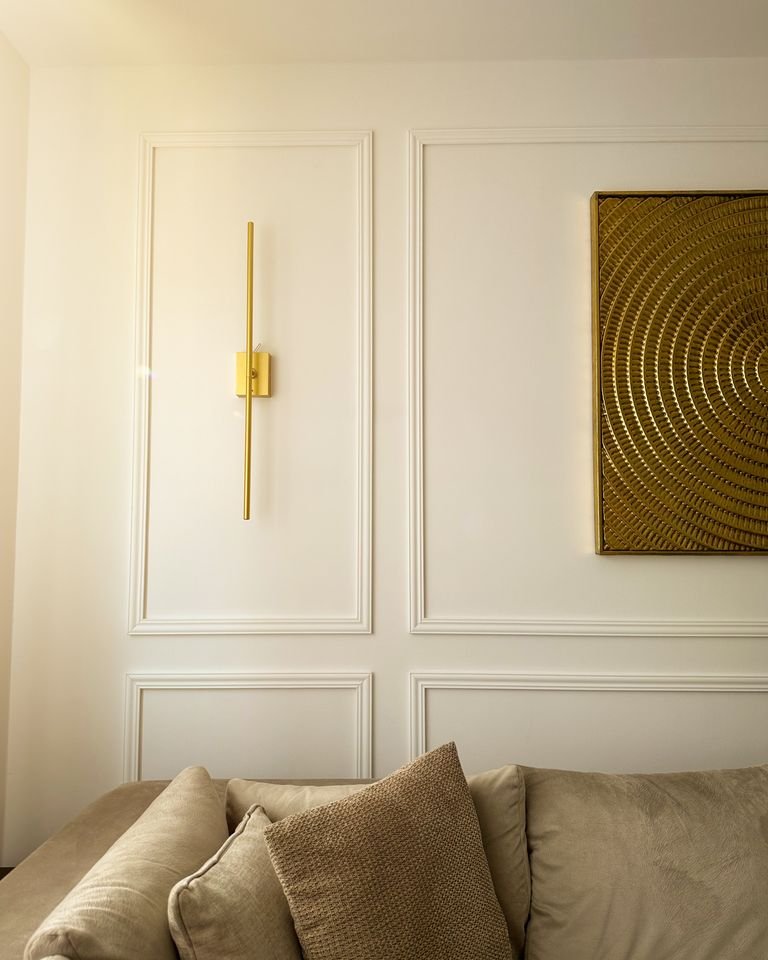 Cream panelled living room wall with a brass wall light