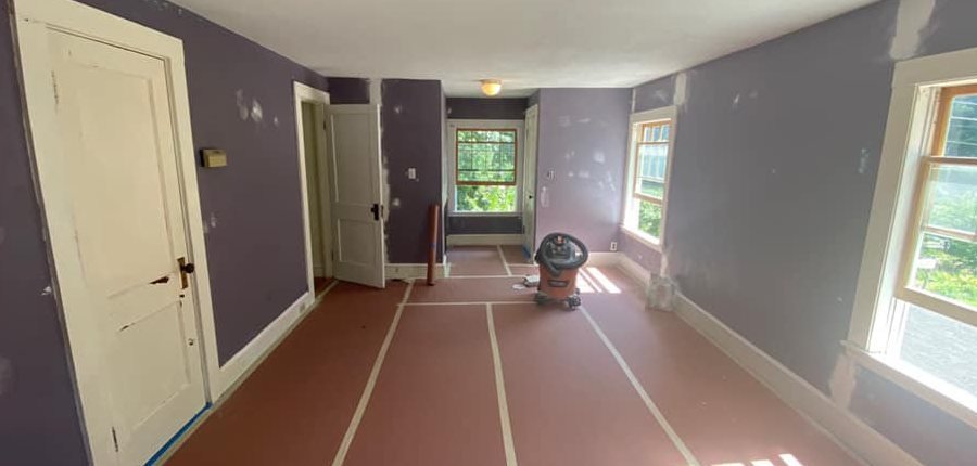The same room before painting: purple walls, the floor covered