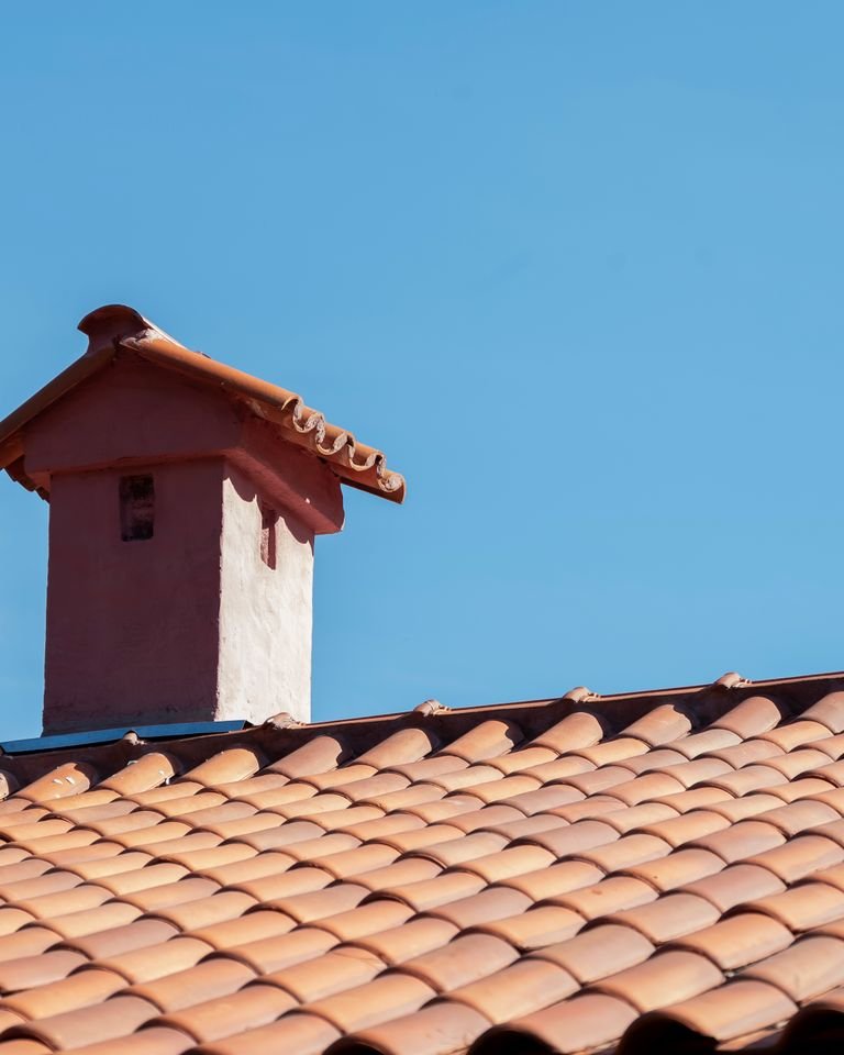 Terracotta roof tiles and a chimney against a clear sky